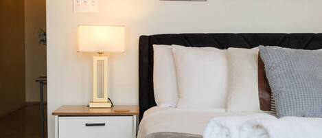 Habitación de hotel con cama, mesita de noche con lámpara y arte abstracto en la pared.