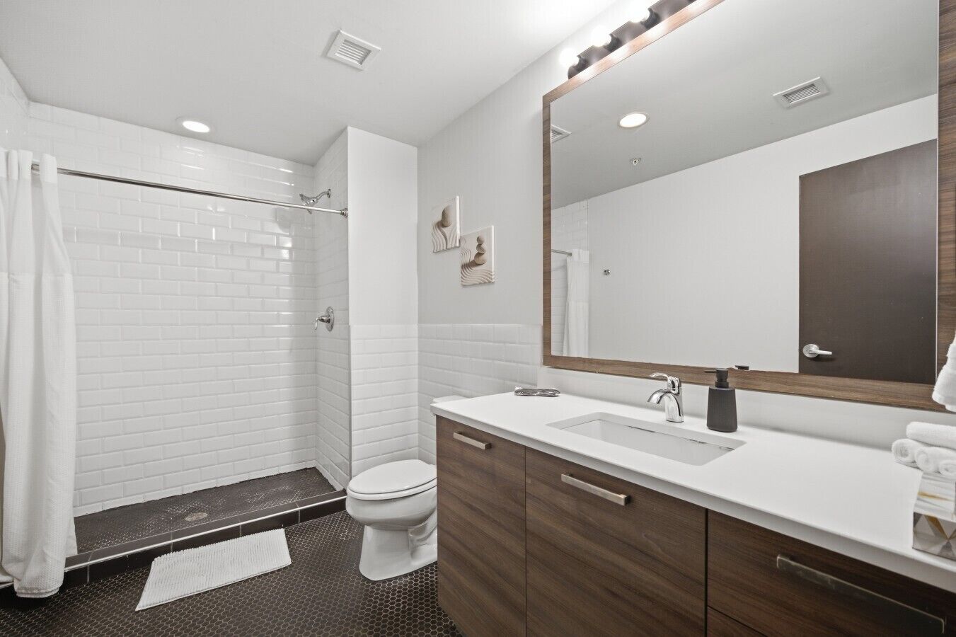 A modern bathroom with a shower, toilet, and vanity.