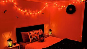 Ein Schlafzimmer mit einem Bett, Nachttischen, einem Teppich und Halloween-Dekorationen.
