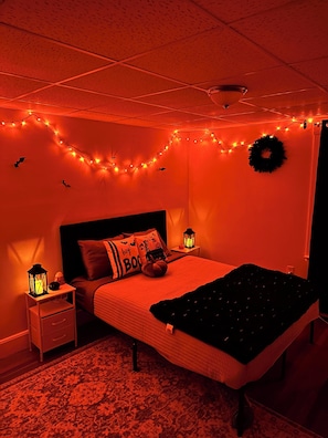 A bedroom with a bed, nightstands, a rug, and Halloween-themed decorations. - The Salem Spookhouse 3BR with Free Parking! Sleeps 8! (Salem)