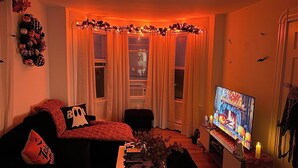 Ein Wohnzimmer mit Fernseher, einer Couch, einem Couchtisch und einer Zimmerpflanze.