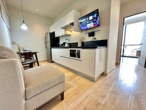 A modern kitchen with a flat-screen TV, a dining area with a table and chairs, and a sofa.