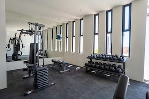 A gym with exercise equipment, dumbbells, and large windows. - Musa del Carmen · Garden Patio & Pool Access (Playa del Carmen)