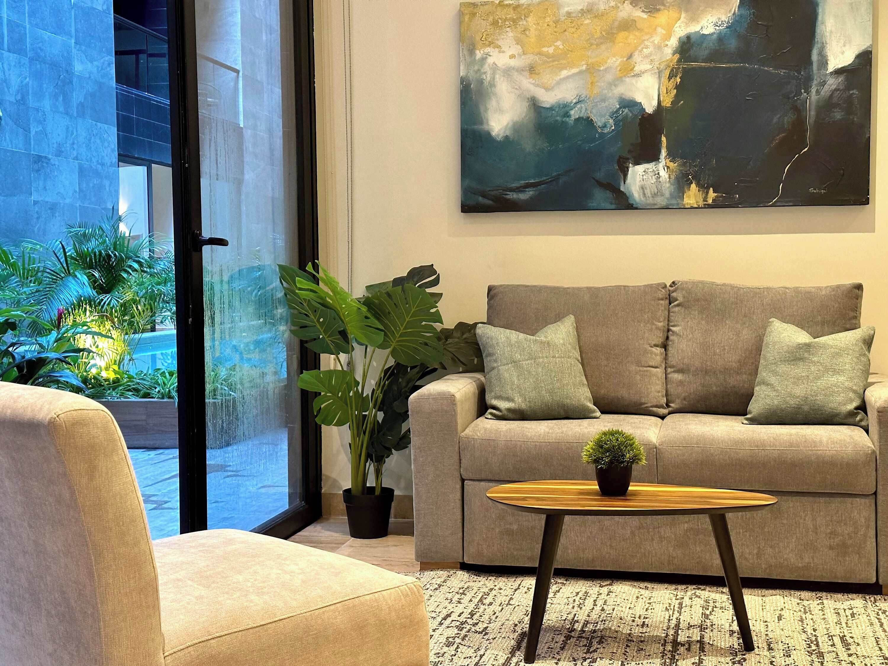 Uma sala de estar moderna com um sofá, uma mesa de centro e um grande quadro abstrato na parede.