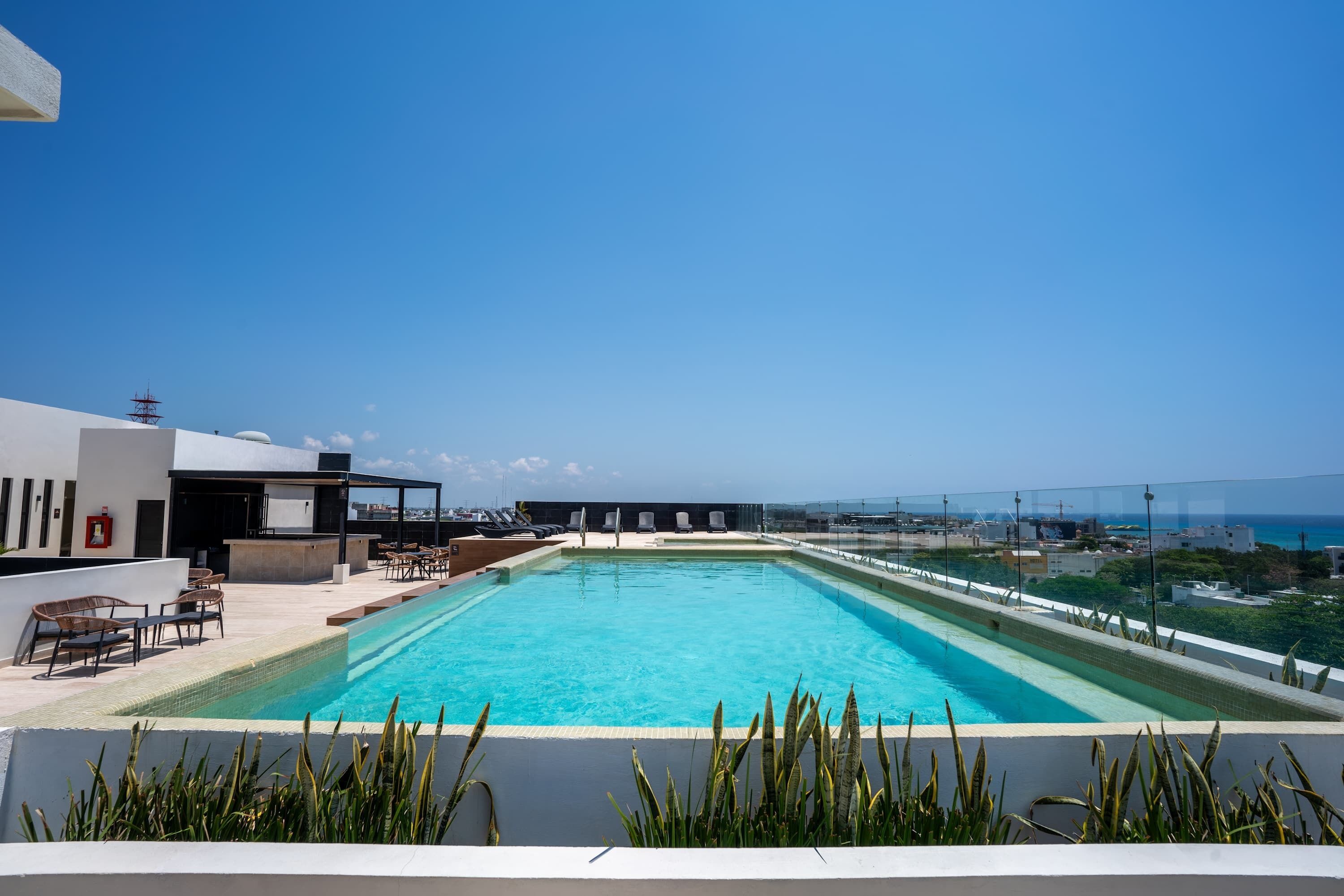 A rooftop swimming pool with lounge chairs and a view of the cityscape.