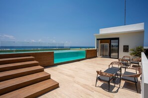 Ein moderner Außenbereich mit Pool, Holzstufen und einer Sitzgruppe mit Stühlen und Tischen.