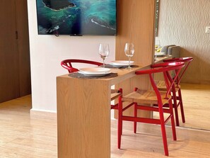 Un coin repas avec une table en bois, des chaises rouges et un téléviseur fixé au mur qui diffuse une vue panoramique.