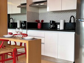 A modern kitchen with white cabinets, a black countertop, and a stainless steel range hood. - Musa del Carmen · Frida Style 1BR w/ Pool & Gym (Playa del Carmen)
