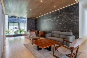 Ein modernes Wohnzimmer mit einer dunklen Marmorwand, einer Holzbalkendecke und einem grauen Sofa.