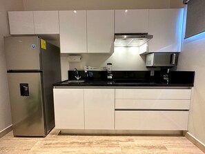 A modern kitchen with a stainless steel refrigerator, a microwave, and a built-in oven. - Musa del Carmen · 1BR w/Washer & Pool Access (Playa del Carmen)