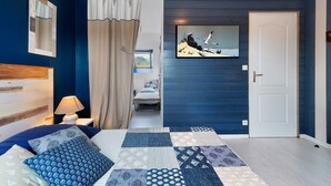 A bedroom with a bed, a nightstand, a lamp, a window, a door, and a wall with a painting.