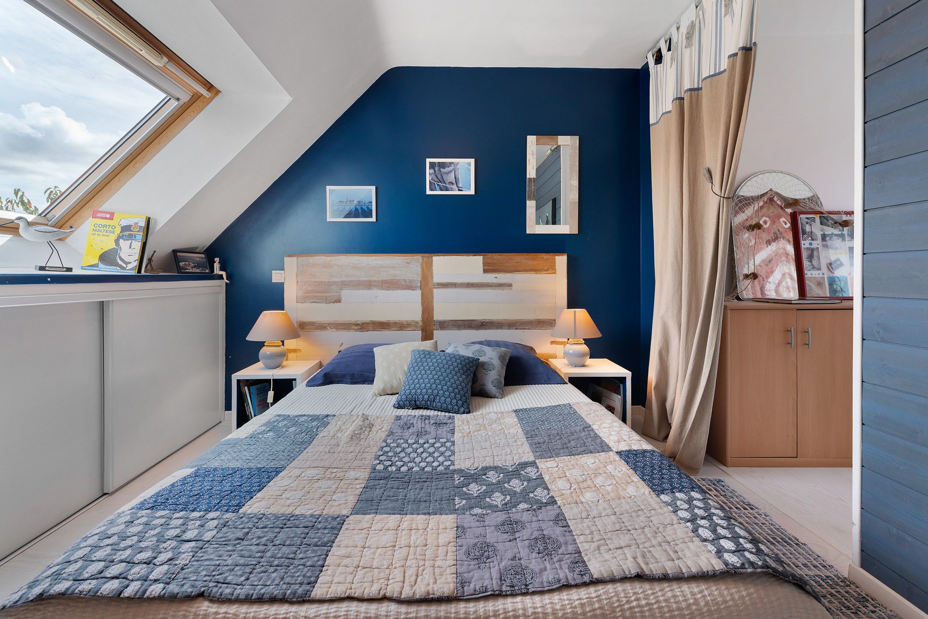 Ein Schlafzimmer mit einem großen Bett, einem Nachttisch, einem Fenster und Blick zum Himmel.