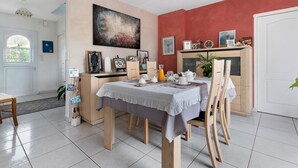 A dining area with a table set for breakfast, a cabinet with various items, and a painting on the wall.
