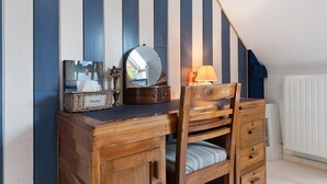 A wooden dresser with a mirror, a lamp, and a wicker basket labeled 'Mouchoirs' in a room with striped walls.