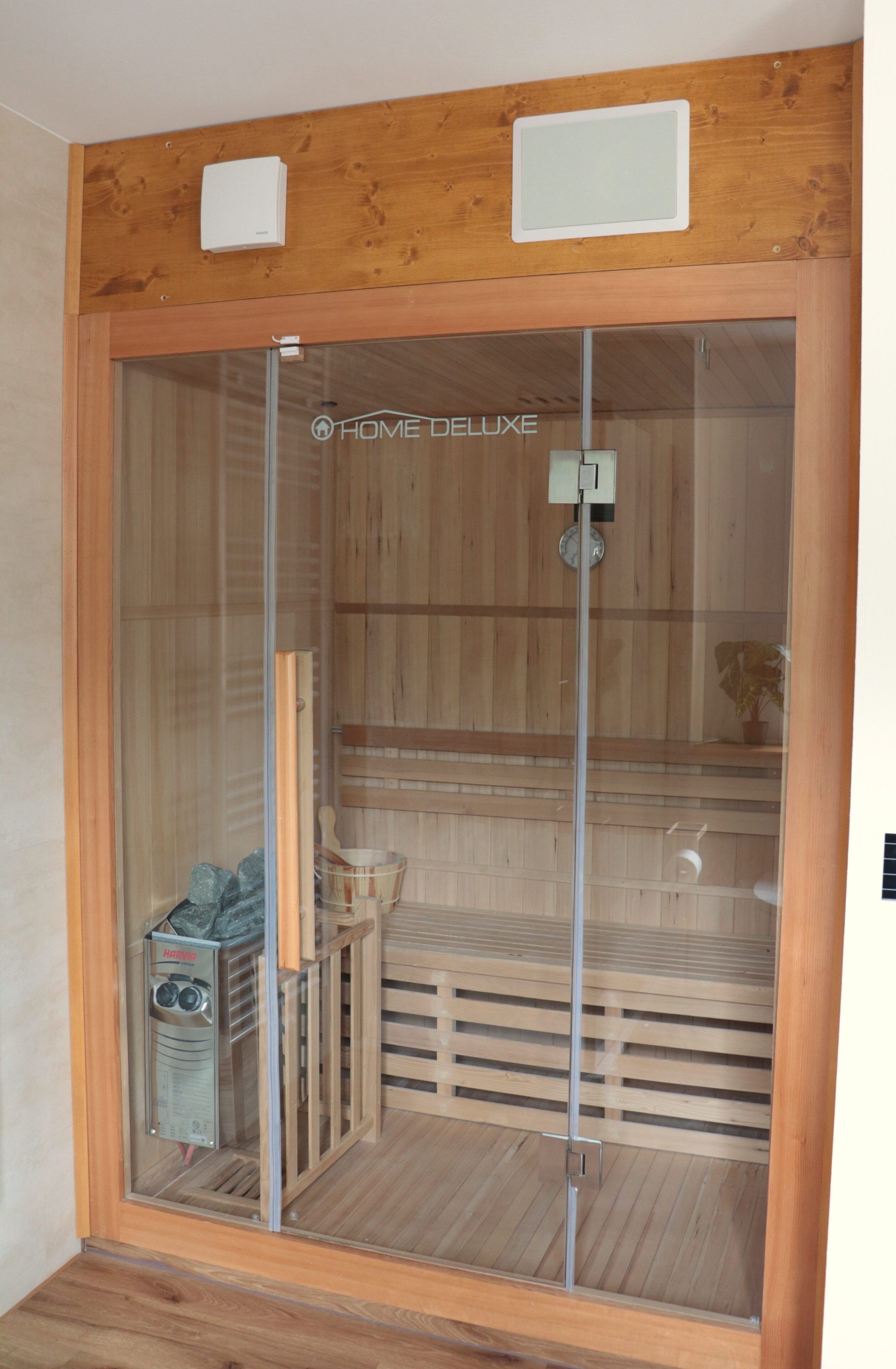 Una sauna con interior de madera, una puerta de vidrio y un calentador de sauna visible a través de la puerta.