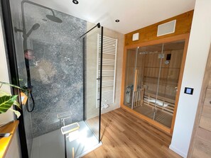 A modern bathroom with a glass shower enclosure, a wooden floor, and a glass door leading to a walk-in closet. - 5-star (DTV) vacation home with plenty of space, a patio, and a fenced-in yard (Wallenfels)
