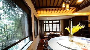 Un comedor con una mesa redonda, sillas y un jarrón con flores amarillas.