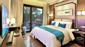 Habitación de hotel con cama, escritorio, televisión y vistas al exterior.