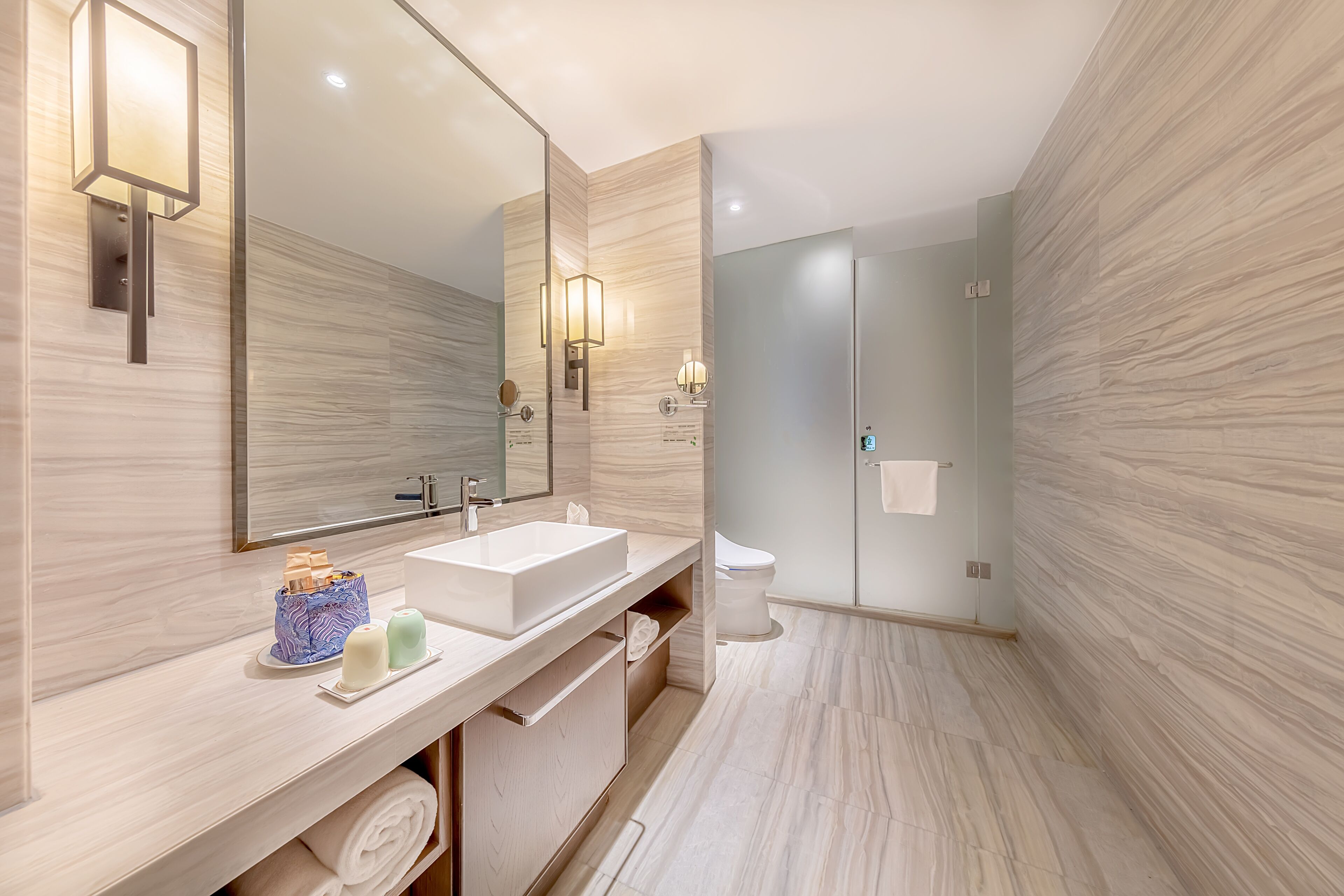 A modern bathroom with a large mirror, a sink, and a toilet.