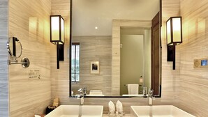 Un baño moderno con dos lavamanos, un espejo grande y luces empotradas.