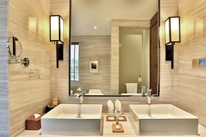 Une salle de bain moderne avec deux lavabos, un grand miroir et des luminaires fixés au mur.