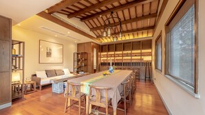 Una habitación amplia con una larga mesa de comedor de madera, un sofá y una estantería.