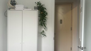 A bedroom with a bed, a wardrobe, a radiator, and a potted plant.