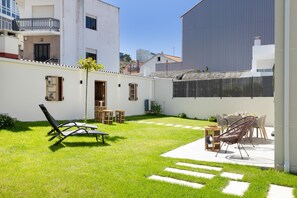 A courtyard with a lawn, outdoor furniture, and a dining area. - Grandma’s House – Renovated Seaside Home in Central Muxía with Garden & Parking (Muxía)