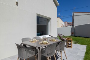 An outdoor dining area with a table set for four, surrounded by chairs. - Grandma’s House – Renovated Seaside Home in Central Muxía with Garden & Parking (Muxía)