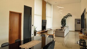 Un salon moderne comprenant un coin repas, un canapé, un téléviseur et une grande plante.