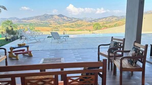 Une terrasse avec mobilier d’extérieur, une piscine et une vue sur les collines.