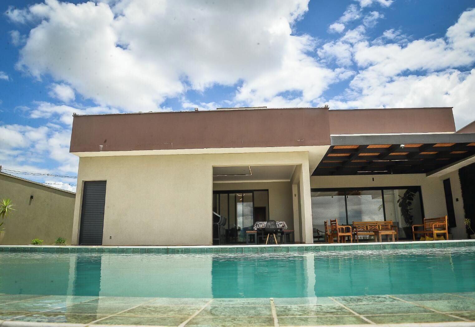 A modern house with a swimming pool, a covered patio, and a dining area.
