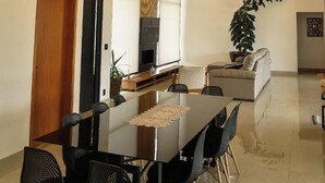 Un espace repas moderne avec une longue table et des chaises, un téléviseur et une plante.