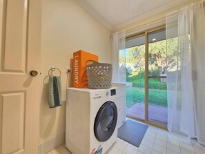 A laundry room with a washing machine, a basket, and a towel rack.