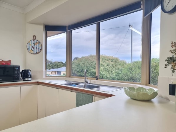 A modern kitchen with a large window, a sink, a microwave, and a coffee maker.