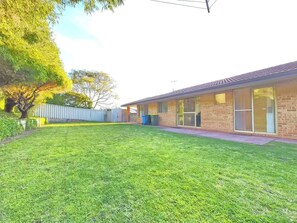 A residential building with a brick exterior, a flat roof, and a well-maintained lawn.