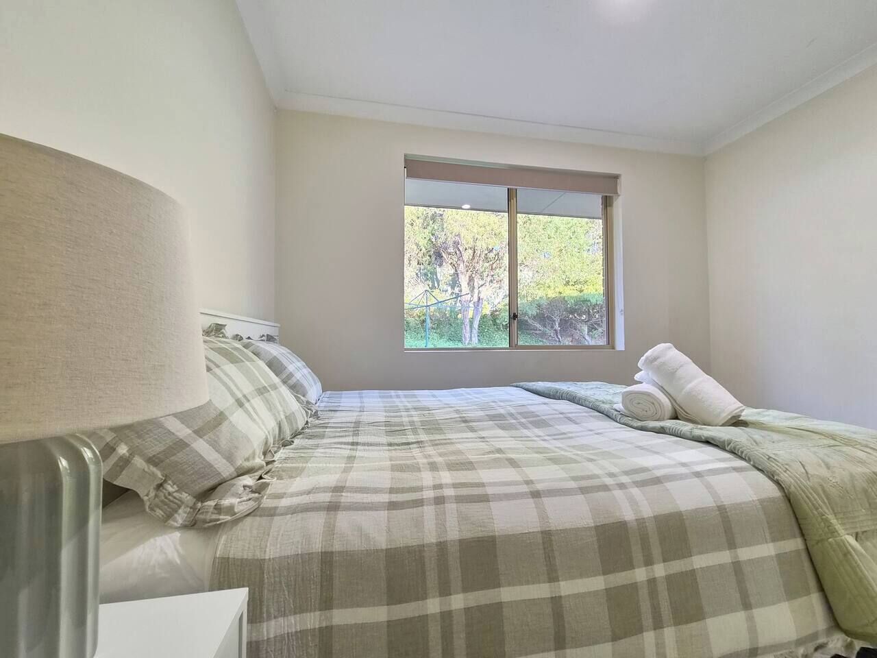A bedroom with a bed, a window, and a lamp.