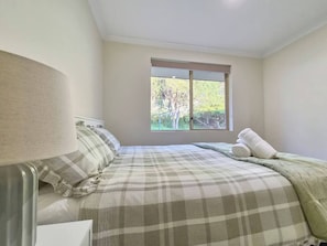 A bedroom with a bed, a window, and a lamp.