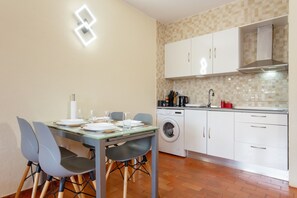 A compact kitchen with a dining table set for four, a washing machine, and white cabinetry. - Peaceful Retreat in Santa Cruz, Madeira — Steps from the Airport (Machico)