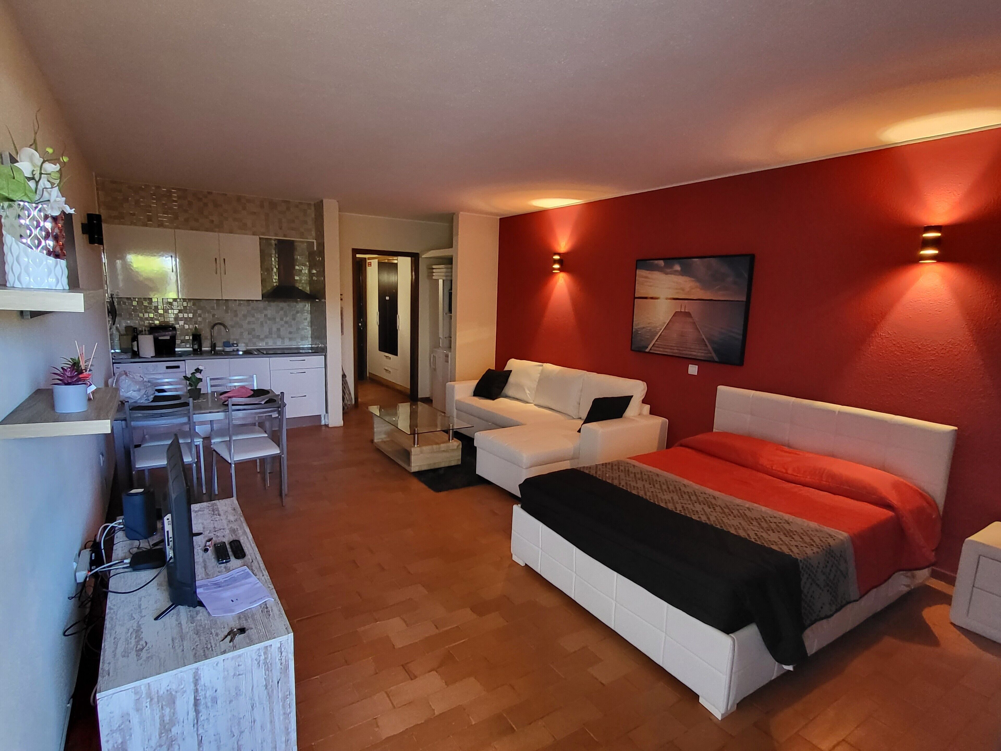 Un espace de vie compact comprenant un coin cuisine, un coin repas et une chambre avec un lit et un canapé blanc.