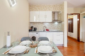 A compact kitchen with a washing machine, a sink, and a dining area set for four. - Peaceful Retreat in Santa Cruz, Madeira — Steps from the Airport (Machico)
