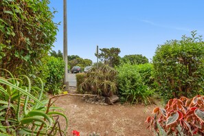 A garden path with various plants and a road with parked cars. - Peaceful Retreat in Santa Cruz, Madeira — Steps from the Airport (Machico)