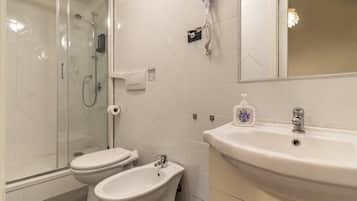 Une salle de bain avec une douche à parois de verre, des toilettes et un bidet.