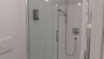 Ducha con cerramiento de vidrio, cabezal de ducha manual y grifo empotrado.
