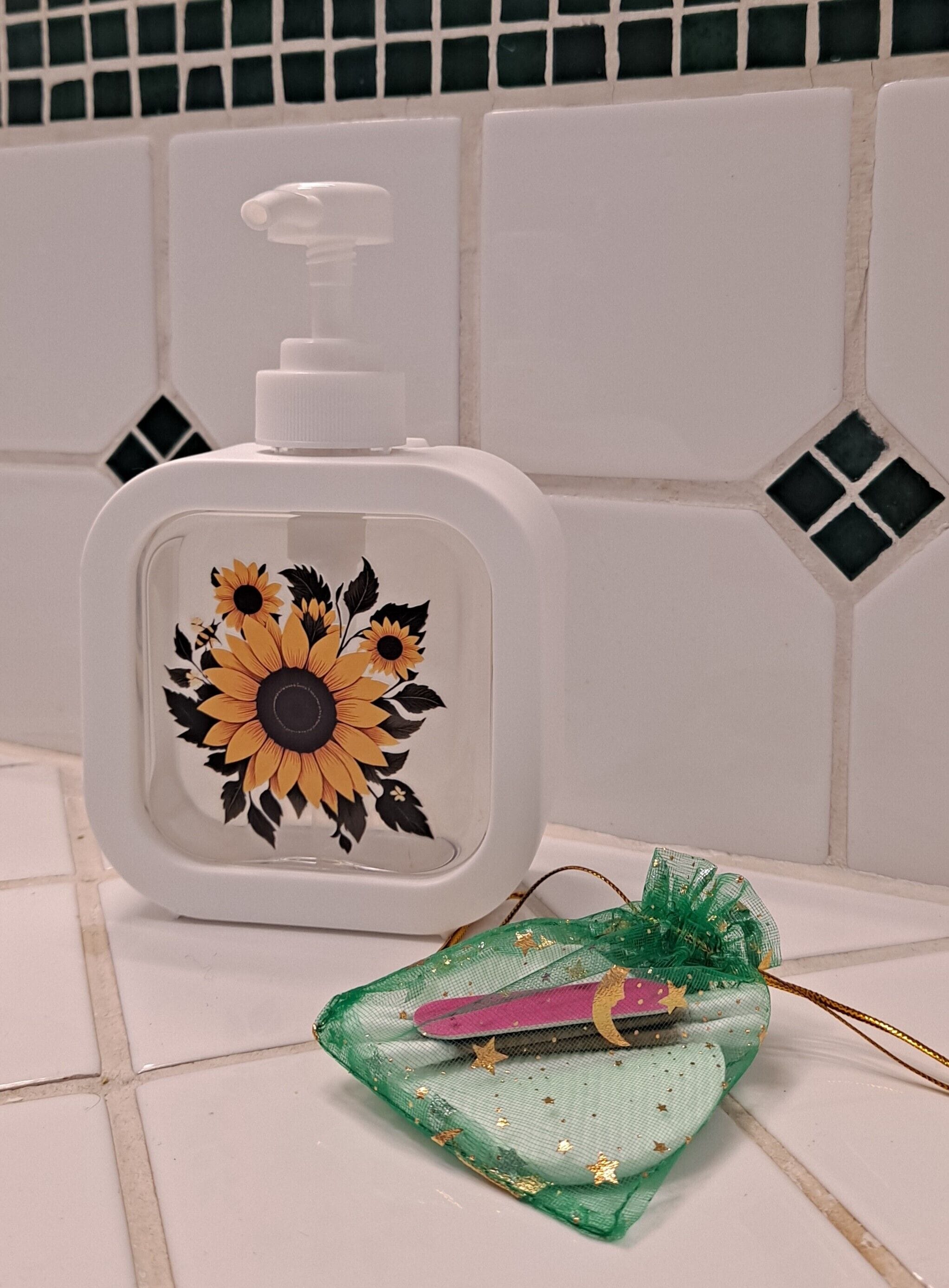 A bathroom with white tiles, a white soap dispenser with a sunflower design, and a green decorative item with gold stars.