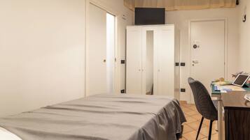 A bedroom with a bed, a desk, a chair, and a wardrobe.