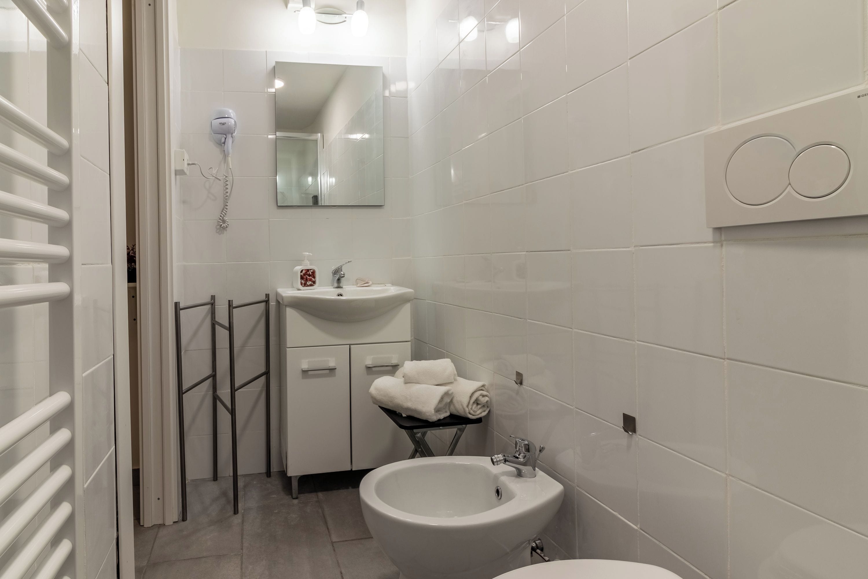 Un bagno moderno con un lavandino bianco, un bidet e un portasciugamani.