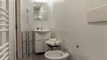 Un bagno moderno con un lavandino bianco, un bidet e un portasciugamani.