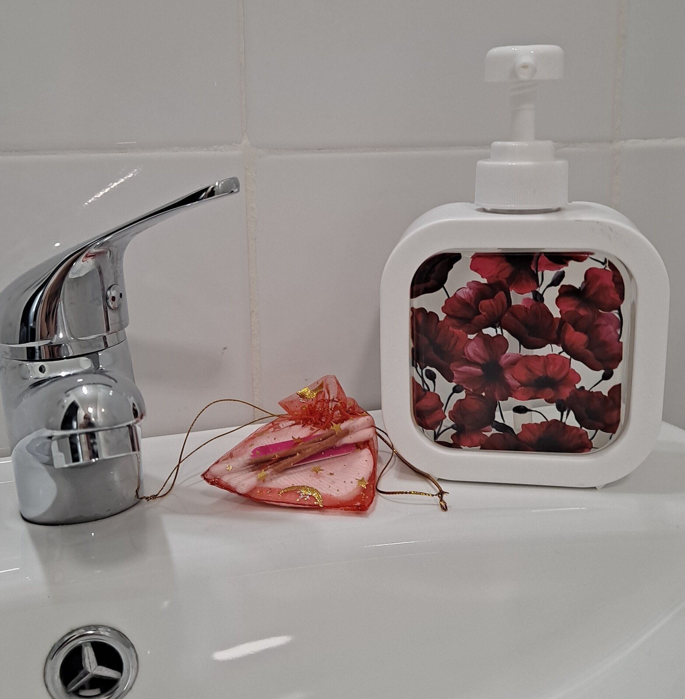 A bathroom sink with a chrome faucet, a soap dispenser with a floral design, and a decorative item with a bow.