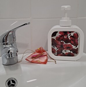 A bathroom sink with a chrome faucet, a soap dispenser with a floral design, and a decorative item with a bow.